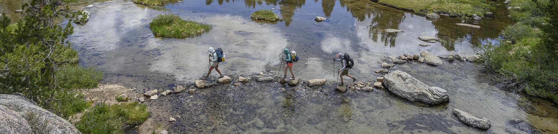 Backpackers rock hopping across a shallow river